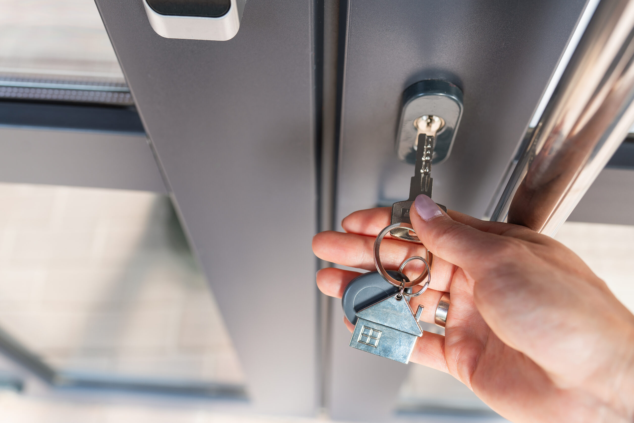 A woman’s hand opens the door with a key on which the keychain hangs at home.